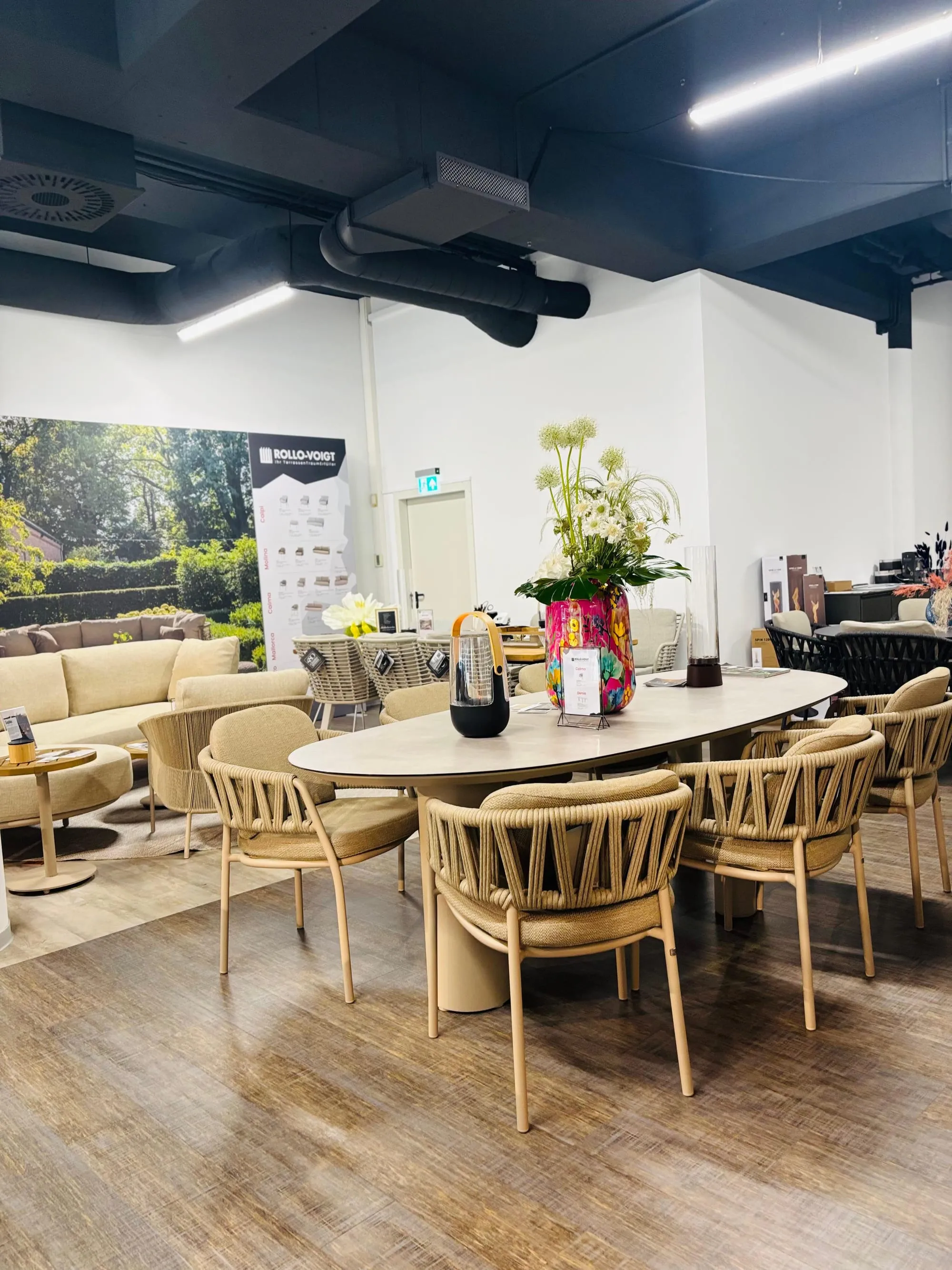 Runder Dining-Tisch mit Blumenstrauß und Geflecht-Stühlen im Store