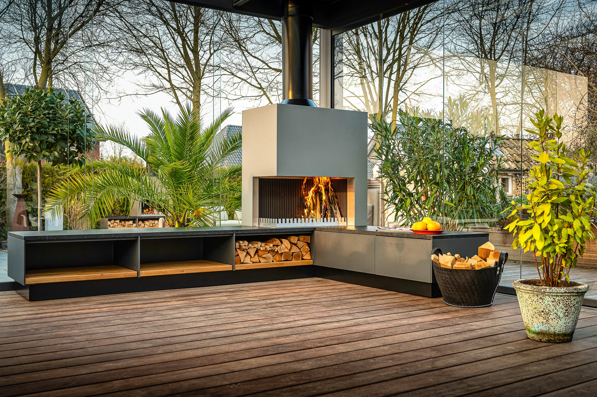 Freiluft Grill-Feuer als Eckmodul mit lodernden Flammen und Holzlager unter der Arbeitsplatte